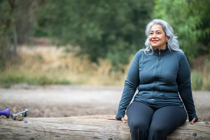 A Hispanic Woman Sits on a Log, Taking a Break From a Hike