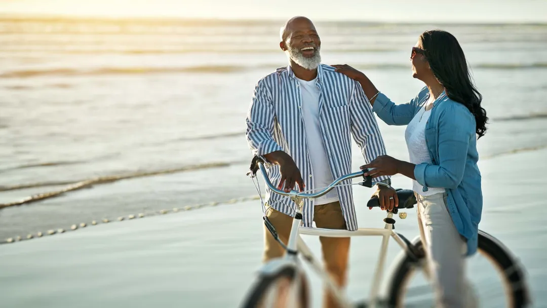 Couple smiling with bicycle on beach