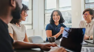 Business people meeting at laptop on desk in open plan office