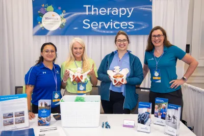 Women attending the Women’s Health and Cancer Prevention Event, an event table featuring therapy services.