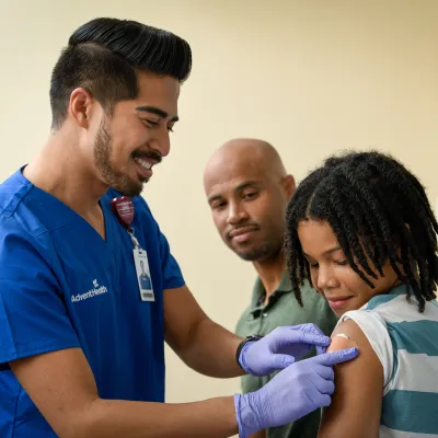 A Provider Puts a Bandage on a Child's Injection Site as They Both Smile.