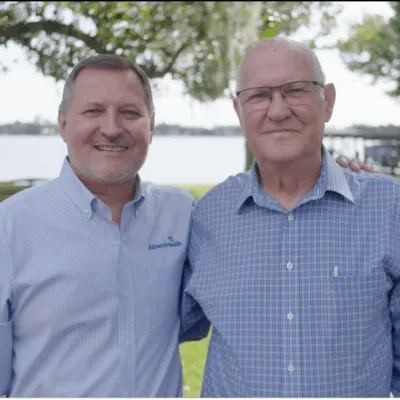 A photo of AdventHealth CEO Terry Shaw and his father standing outside in front of a lake.