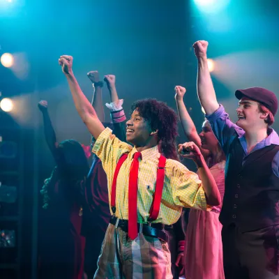 A group of young people raising their fists on a stage.