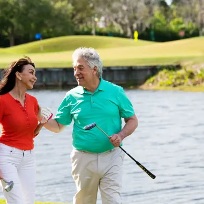 An older couple walking on a golf course.
