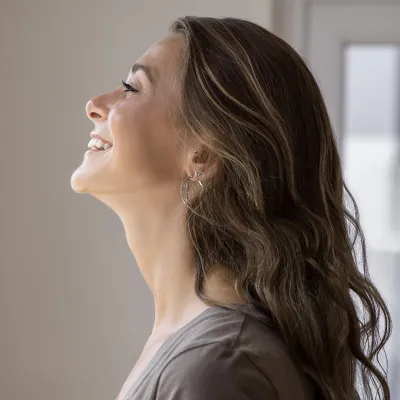 Woman smiling as she looks outside from her window.