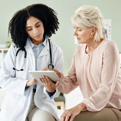A woman looking at medical info on a tablet with her doctor.