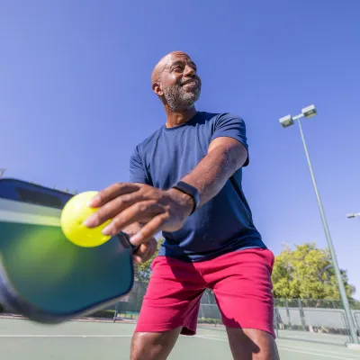 A man playing pickleball outdoors.