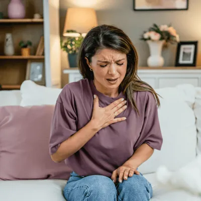 Woman Sitting on her couch clutching her chest with pain