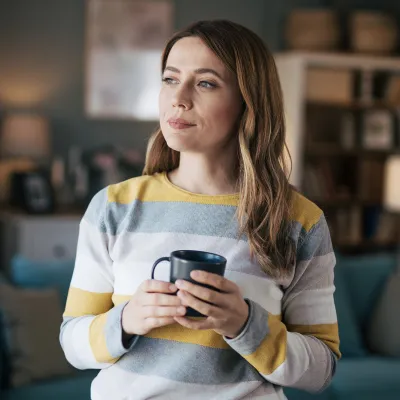 Woman holding a cup of coffee in her living room