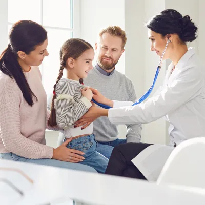 Doctor interacting with child patient with parents