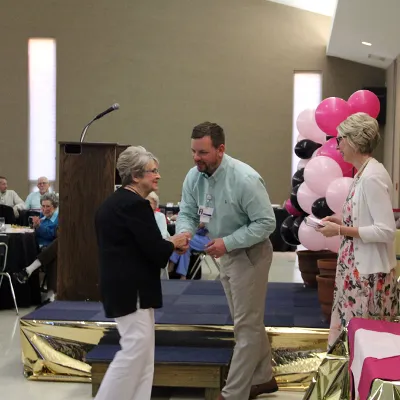 A group of two women and a man receiving an award at a ceremony.