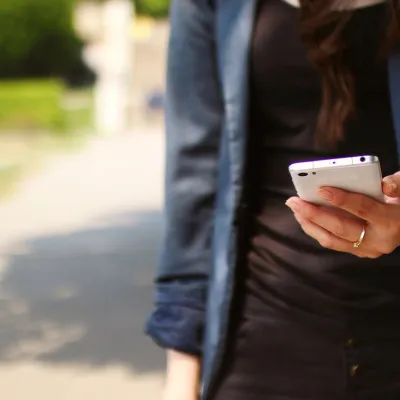 A woman standing while holding a cell phone.