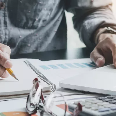 an working on laptop while taking notes