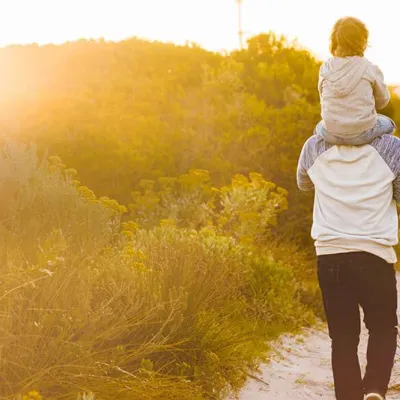 A family walking through a sandy trail as the sun sets