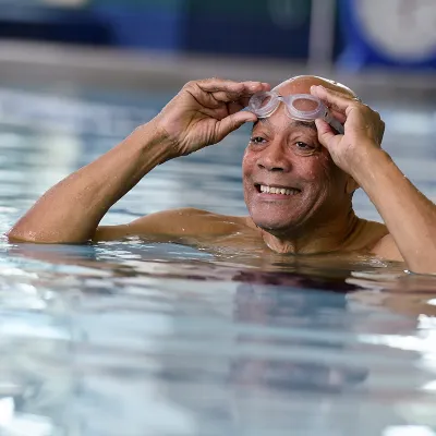An older man puts on his goggles in an indoor exercise pool