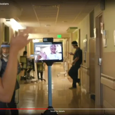 A child patient waves at a staff member in the hall as she controls her robot