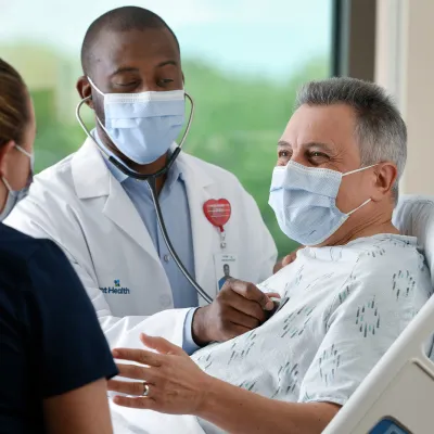 Man in an AdventHealth emergency room with a doctor and nurse.