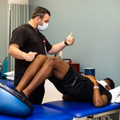 A patient doing a rehab exercise while being guided by the doctor