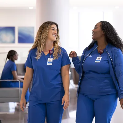 Two nurses walking together having a conversation.