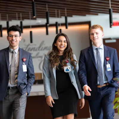 Three young professionals walking in the hallway of an office building