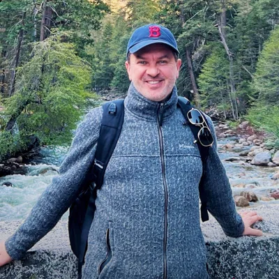 Alex Frost standing on a bridge over a river.