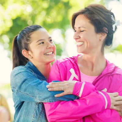 A daughter hugs her mother as they participate in a breast cancer walk.