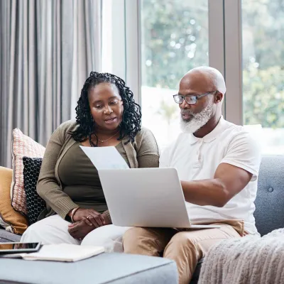 Man and woman reviewing paperwork with computer on lap
