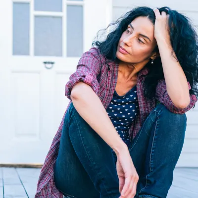 A woman sitting on the porch looking concerned.
