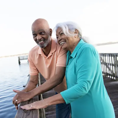 Older couple leaning on the pier looking at the lake