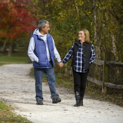 Couple walking down a path outdoors in the fall holding hands.