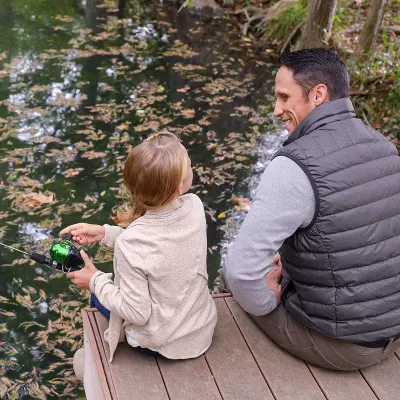 A father and daughter sitting on a pier while fishing