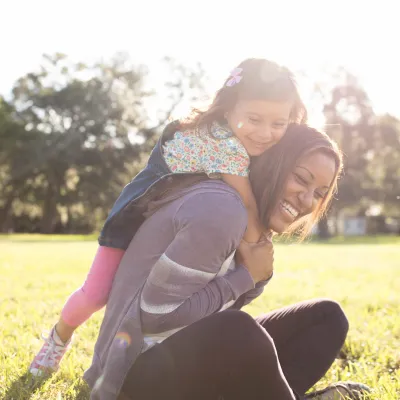 Daughter climbing on mom outdoors