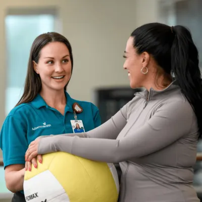 AdventHealth physician talking to patient holding yellow excercise ball