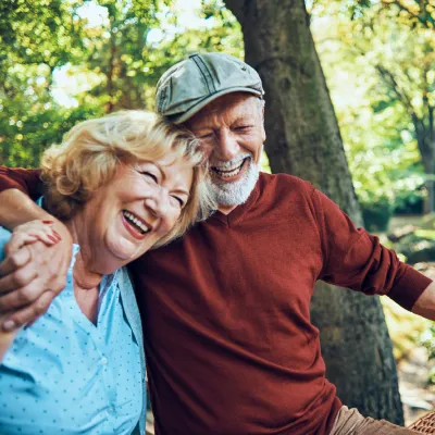 Man and woman laughing together in a forest.