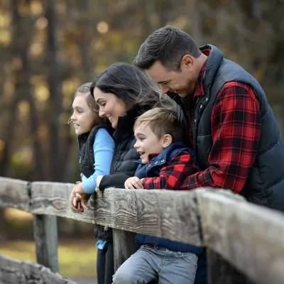 A family of four leaning on a fence while outdoors in the winter.