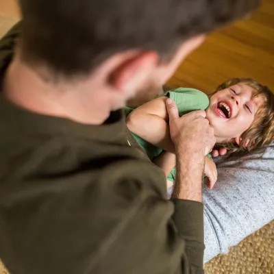 A dad is tickling his son.