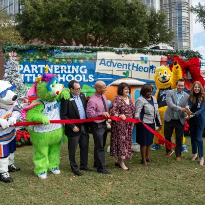 AdventHealth and partners from the Orlando Magic, Florida Citrus Sports, Second Harvest Food Bank and local school districts cut the ribbon on AdventHealth's "Drive Out Hunger" Holiday Bus.