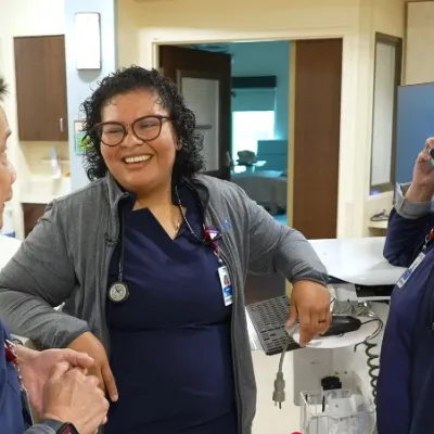 A group of nurses chat on a hospital unit floor. 