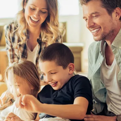 Family playing and laughing together in a sun filled living room of their house.