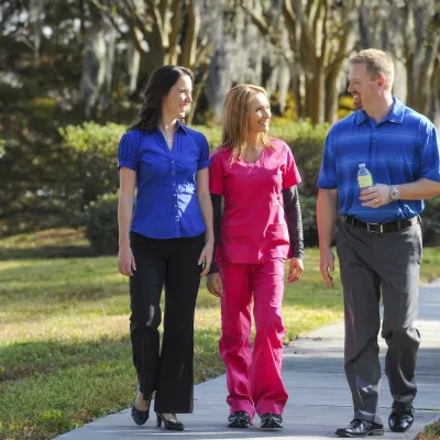Three employees walk on a sidewalk.