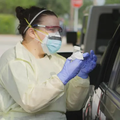 Health Care employee talking to a patient at a drive up testing site