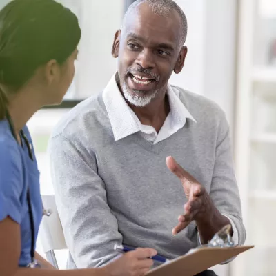 A man asks questions at his appointment with his doctor.