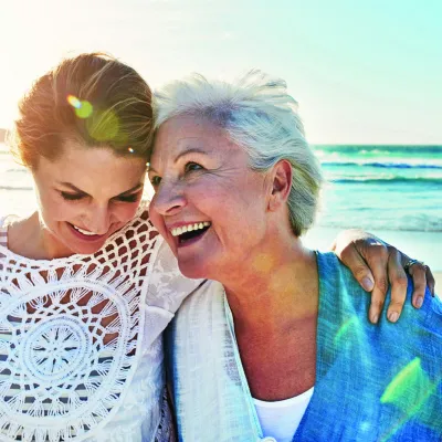 Mother and adult daughter walking on the beach together