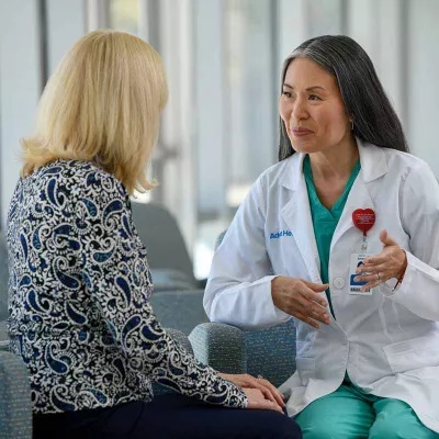 Gray-haired female doctor speaks with blonde patient