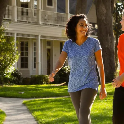 Two women walking and smiling in a neighborhood