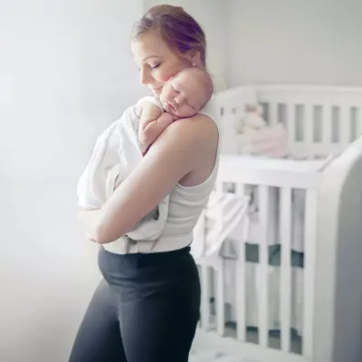 Woman holding baby in home nursery