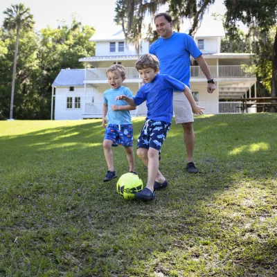 A father playing soccer with his children.