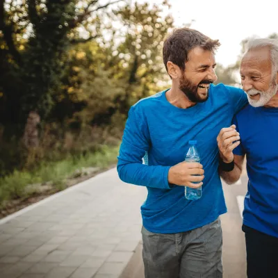A mid-30s man walking outdoors with his father.