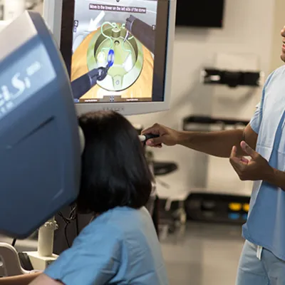 Surgeon using a da Vinci Surgical System simulation with another surgeon watching.