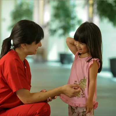 A nurse speaks to a child in the hospital hallway.